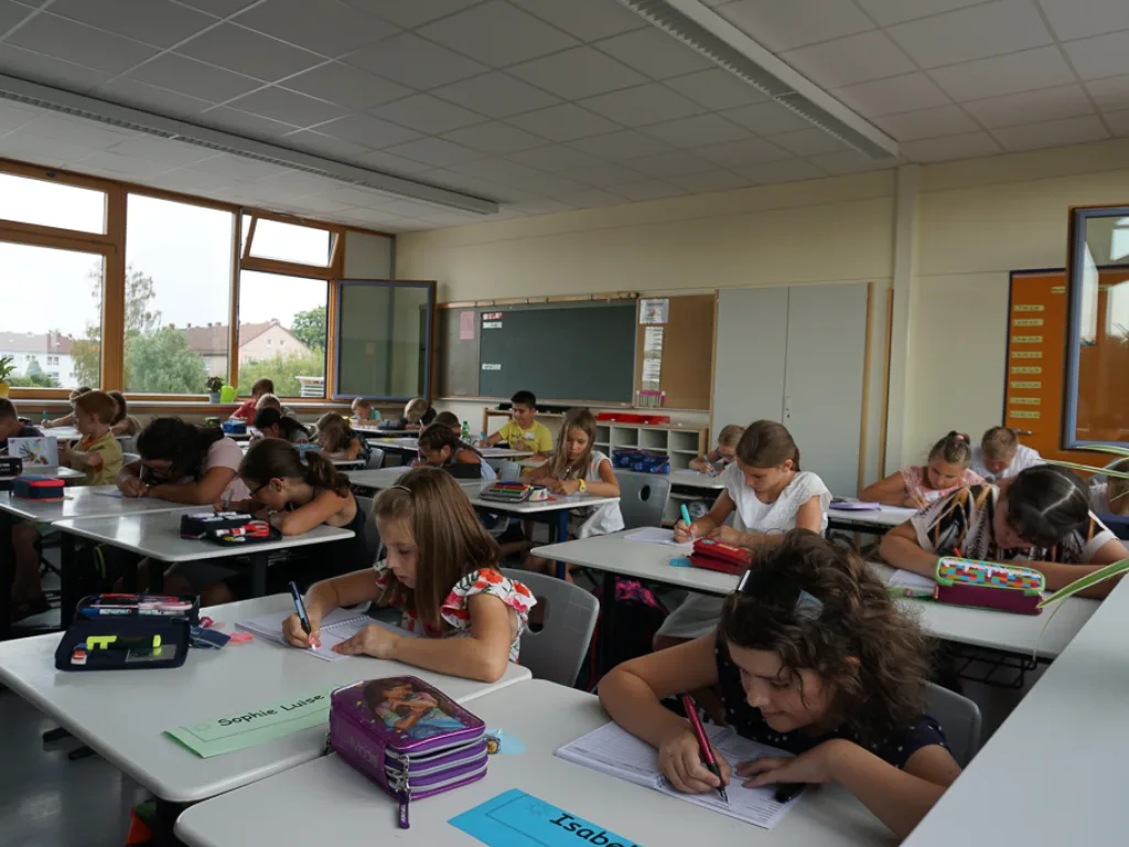 Kinder arbeiten konzentriert an ihren Tischen.